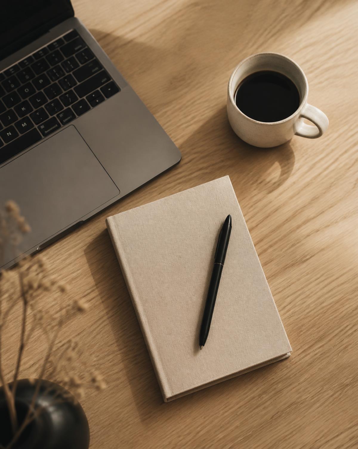 Bureau en bois clair avec ordinateur portable, carnet et café